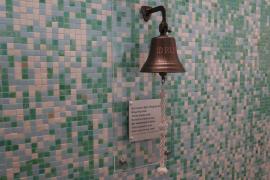 A survivor's bell is pictured on a tiled wall, along with a plaque.