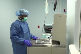 A person in surgical scrubs stands in front of a large machine.