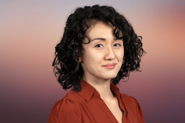 Asian woman with dark curly hair wearing a rust-colored collared shirt
