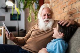 Senior man laughing with grandson while ruffling his hair