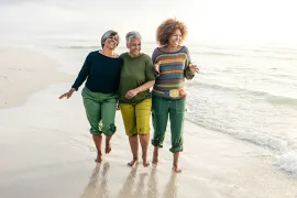 Three women walk on the beach together