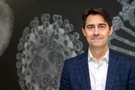 A man wearing a suit in front of a background of microscopic images