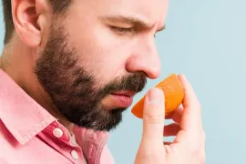 A person smelling a sliced piece or orange