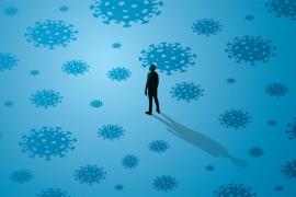 Silhouette of a person standing among large illustrations of viruses on a blue background.