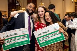 Three RMC graduates stand together smiling, as two hold signs reading I Matched! General Surgery at LSU