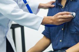 Physician uses stethoscope to listen to patient's heart.