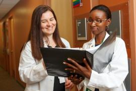 Two nurses in a corridor consulting a file