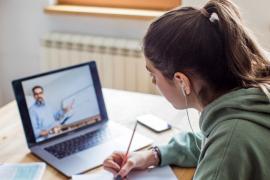 A student taking notes while viewing an online lecture
