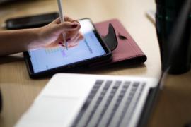 Student using a tablet with stylus and a laptop for online learning