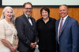 Four people stand together smiling