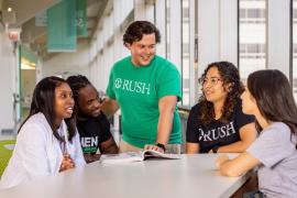 A group of students in conversation with an open textbook on the table in front of them