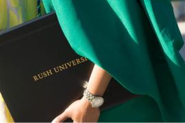 Close-up of a Rush University diploma held by a graduate wearing commencement robes