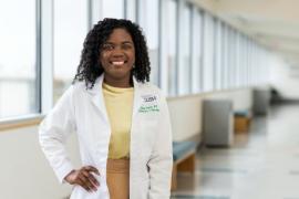 A smiling doctor standing by windows in a corridor