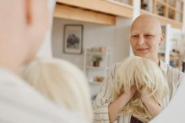 Woman looking in mirror holding wig