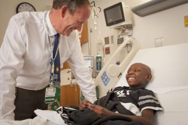 Doctor at bedside talking with smiling child. 