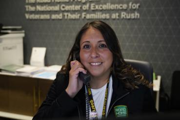 Dee Garcia, a woman with long brown hair and a smile on her face, talks on the phone while working at the Road Home Program.