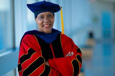Diane Howard, PhD, MPH, FACHE, stands in graduation regalia.