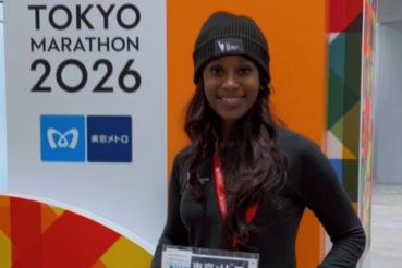 A woman wearing a hat stands next to a Tokyo Marathon 2026 sign
