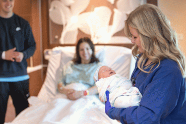 Nurse holds baby as parents look on