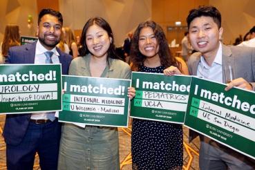 Four students smile and hold up signs saying I Matched