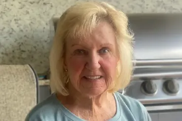 Patient Ulema Hirsch sits on a patio in front of a grill.