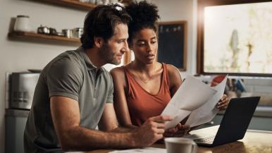 Young Couple In KItchen on Computer Comparing Health Plans During Open Enrollment