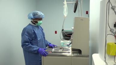 A person in surgical scrubs stands in front of a large machine.