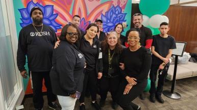 Rush faculty smile in front of a mural in the Cultural Center