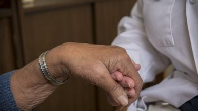 Chaplain holds patient's hand