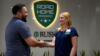 Two people shake hands inside RUSH's Road Home Program.