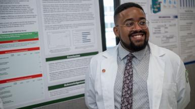 College of Nursing student smiles in front of their capstone presentation