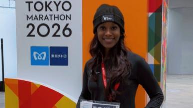 A woman wearing a hat stands next to a Tokyo Marathon 2026 sign