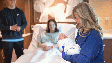 Nurse holds baby as parents look on