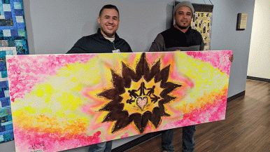 Artist Johnny Felix (right) and Omar Ramos, Waterford Place program development and operations manager, hold the painting Felix created to honor people dealing with cancer.
