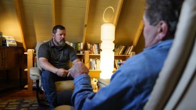 Reg McCutcheon, a trained trauma therapist, speaks with a client at his practice