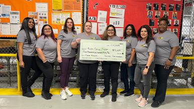 Roscoe team members showcase a novelty check representing a gift to RUSH Cancer Center after a monthlong fundraiser and matching contribution from President Jim Buik.