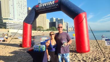 Tom Boucher and Melinda Remaly stand on Ohio Street Beach for a previous Swim Across America Chicago Open Water Swim.