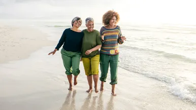 Three women walk on the beach together