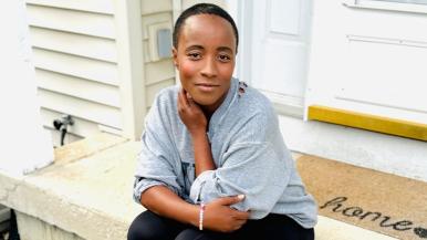 Erica Schwartz sitting on a porch step with a welcoming mat that reads "Home".