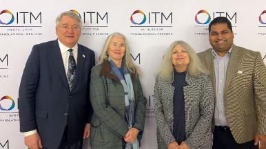 Four people standing in front of a backdrop wth the ITM logo