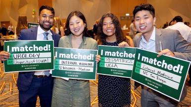 Four students smile and hold up signs saying I Matched
