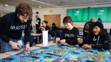 Three people work together making a large blanket