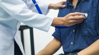 Physician uses stethoscope to listen to patient's heart.