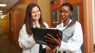 Two nurses in a corridor consulting a file