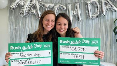 Two students holding Rush Match Day posters