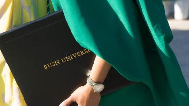 Close-up of a Rush University diploma held by a graduate wearing commencement robes