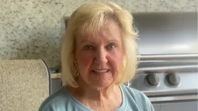 Patient Ulema Hirsch sits on a patio in front of a grill.