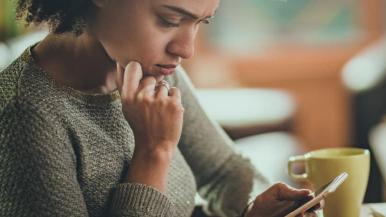A woman looks at her phone in a coffee shop.