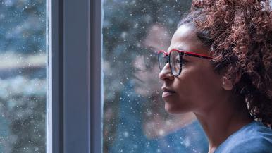 Woman staring out window at snow