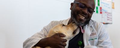 A nurse smiles as a dog tries to lick.